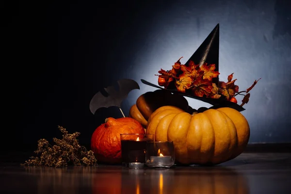 För att skapa en atmosfär av halloween lögn gula och orange pumpor, brinnande aromatiska ljus, ligger en gren av torrt gräs och ritningar av svarta fladdermöss — Stockfoto