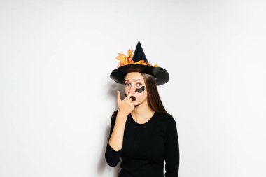 Kız kendini bir kostüm Cadılar Bayramı için beyaz bir arka plan üzerinde yapar