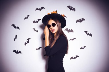 Beyaz bir arka plan üzerinde siyah gözlüklü cadı elbiseli kız