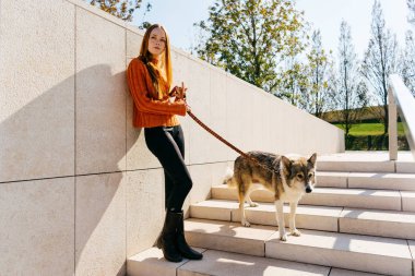 Bir kız köpeğiyle parkta merdivenlerde duruyor