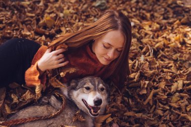 Kız sonbahar yaprakları köpeğiyle yatıyor.