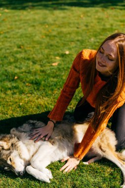 gülümseyen kız köpeğini parkta çim üzerinde yalan