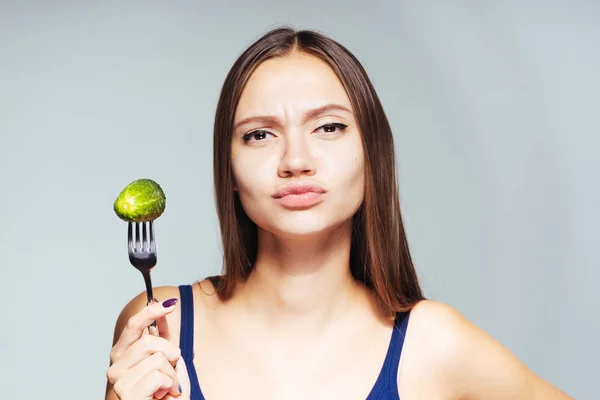 Das Mädchen blickt wütend nach vorn und hält eine eingelegte Gurke in ihren Händen — Stockfoto