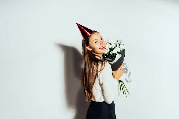 Chica feliz en un sombrero festivo sostiene un ramo de flores en sus manos — Foto de Stock