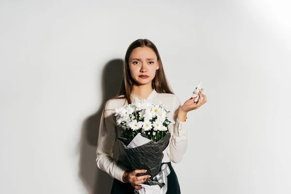 Bouleversée fille tenant un grand bouquet de fleurs blanches dans les mains — Photo