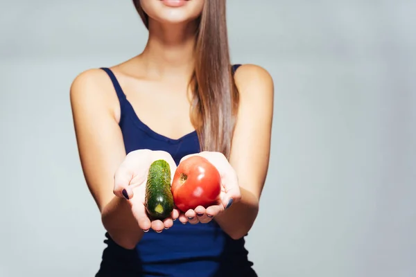 Dívka v modré košili drží pár zeleniny v dlaních — Stock fotografie