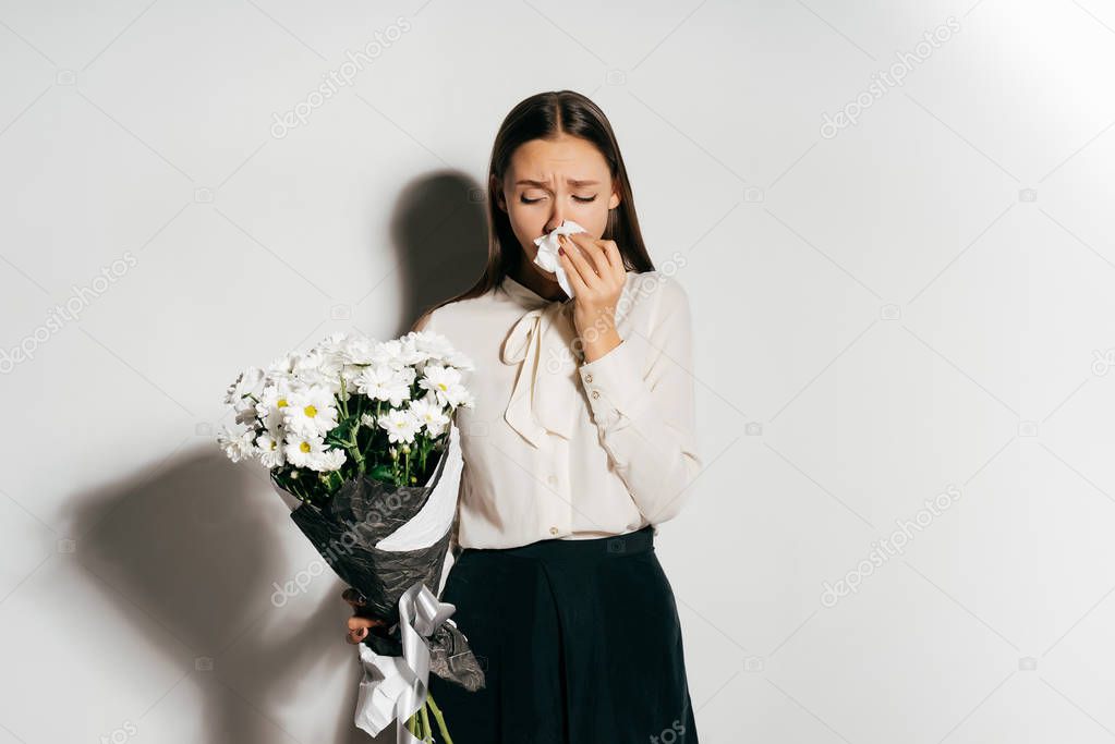 A frustrated girl in a white shirt is holding a bouquet of flowers