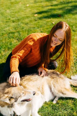 Kız Köpeğini okşayarak sonbahar parkta çim üzerinde yalan