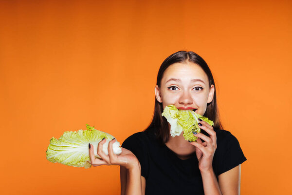 a girl with a smile on her face eats lettuce leaves