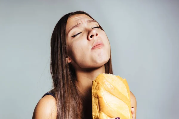 Ein Mädchen mit dem Vergnügen, ihr Brot auf weißem Hintergrund zu essen — Stockfoto