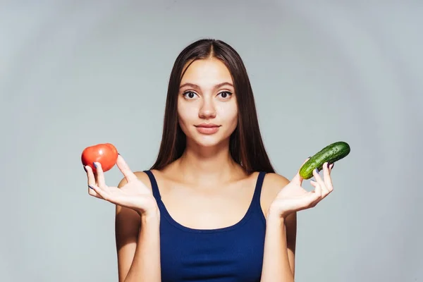 Dívka na šedém pozadí drží v rukou zelenina — Stock fotografie