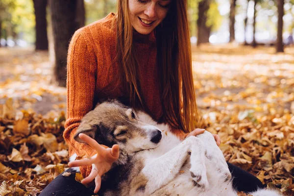 Girl in autumn park playing with her dog — Stock Photo, Image