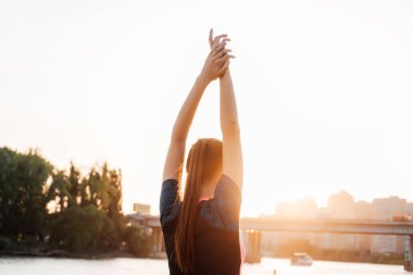 Sportif kız günbatımında nehrin yanında spor yapıyor