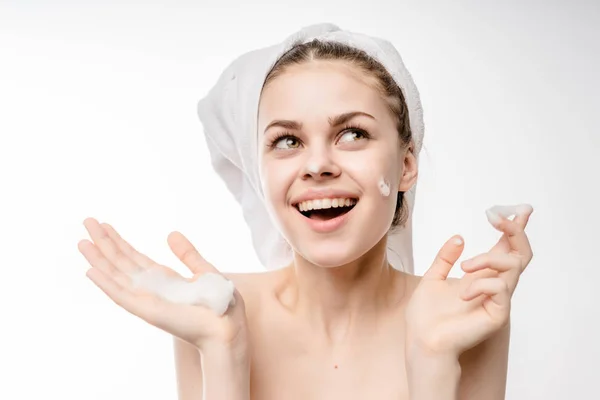 Happy smiling girl with clean skin and white towel on her head applying foam on face — Stock Photo, Image