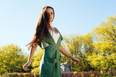 uzun siyah saçlı ve parkta yürüyüş yeşil renkli bir elbise ile güzel kız