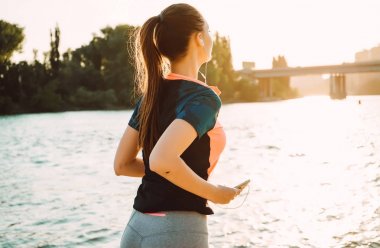 nehre kulaklıklar, güneşin çevresinde kaçan genç atletik kız