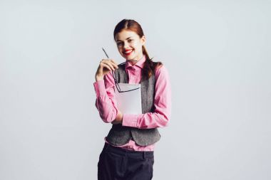 Kızıl saçlı gülen kız kırmızı ruj, pembe gömlek ile bir klasör belgeler ve bir kalem tutuyor