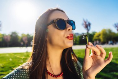 Mutlu gülümseyen komik surat kız darbe karahindiba, yaz güneş gözlüğü, günbatımı