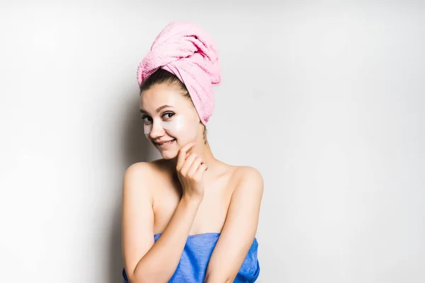 Härlig leende flicka med en rosa handduk på hennes huvud och silikon fläckar under ögonen — Stockfoto