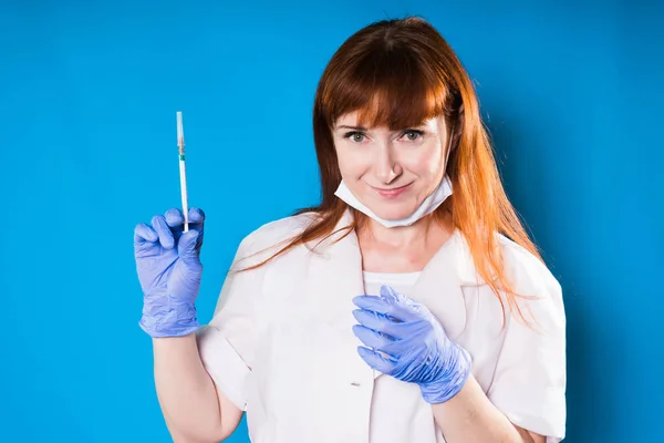 Medico donna adulta in vestaglia medica bianca tiene una siringa tra le mani e sorride — Foto Stock
