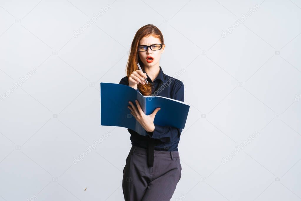 red-haired surprised successful girl in office strict clothes writes something in a folder