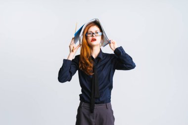 Kızıl saçlı kız gözlük ve kırmızı ruj ile bir klasör belgeler ile boyundan büyük tutar ve yorgun görünüyor