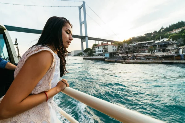 Любопытная девушка с удивлением смотрит на город, прогулка на лодке по Босфору, современный мост — стоковое фото