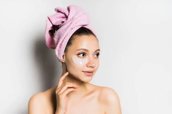 Krásná mladá dívka s čistou kůží, s růžový ručník na hlavě, usmíval se a hledat dál — Stock fotografie
