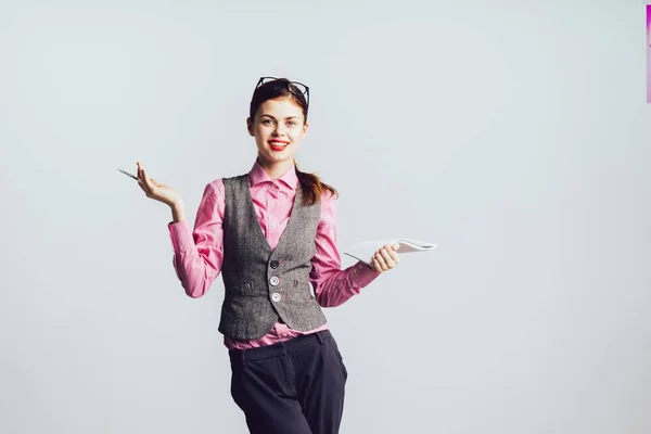 Счастливая успешная современная девушка в розовой рубашке держит ручку и бумагу — стоковое фото
