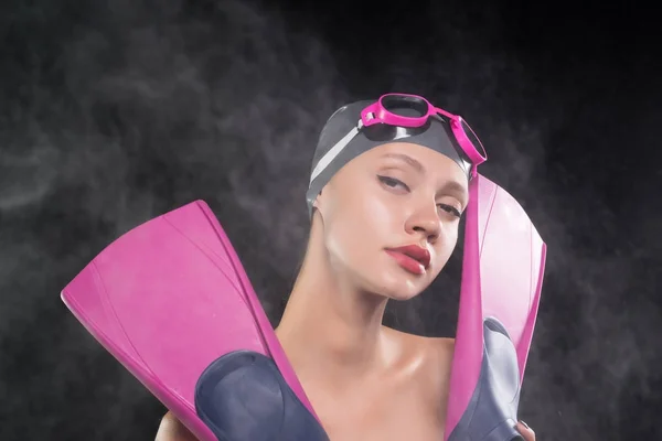 Bella nuotatore ragazza fiduciosa tiene pinne rosa, sulla testa un cappello da bagno e occhiali — Foto Stock