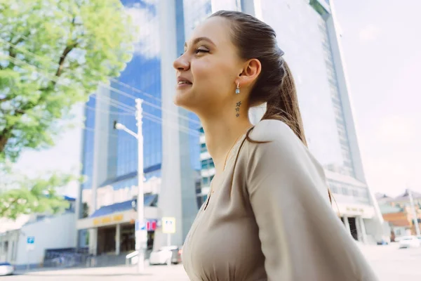 Beautiful laughing girl in beige dress walking around the city — Stock Photo, Image
