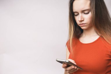 genç güzel kız bir turuncu tişört smartphone bakar ve üzgün görünüyor