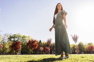 Yeşil çimlere park boyunca yürüyüş uzun elbiseli şık uzun saçlı kız