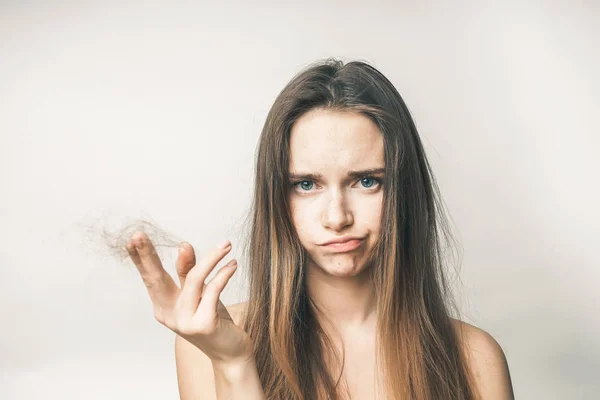 Jovem triste com cabelo comprido segura um pedaço de cabelo na mão — Fotografia de Stock