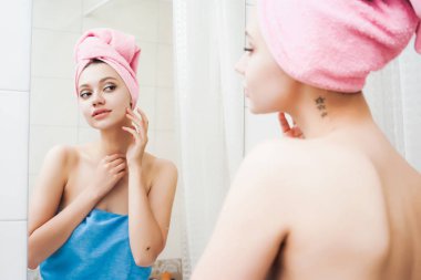 boynunda dövme olan güzel bir kız, bir pembe havlu başında kendini Aynaya bakar