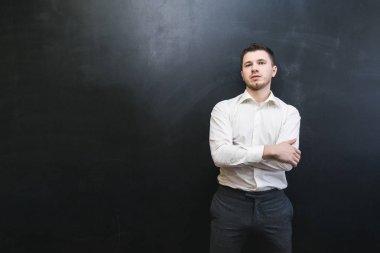 karanlık bir duvara poz bir Beyaz tişörtlü şık kendine güvenen adam