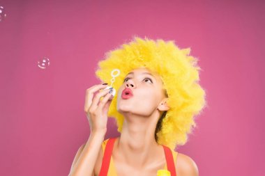 genç kız başına sabun köpüğü üfleme sarı palyaço peruk ile