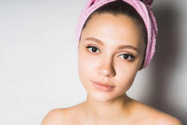 Giovane bella ragazza con la pelle bianca pulita e con un asciugamano rosa sulla testa guardando la fotocamera — Foto Stock
