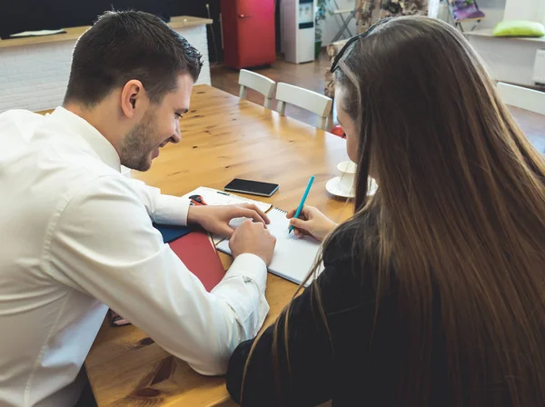 Молодые уверенные парень и девушка сидят за столом, работая в офисе — стоковое фото
