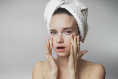 başında beyaz bir havlu ile genç kız kendini elleriyle yüz masajı yapar