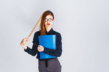 Gözlük ve şık giysiler ile modern bir genç kız bir klasör belgeler ve bir cetvel ile tutarak ve şaşırmış görünüyor