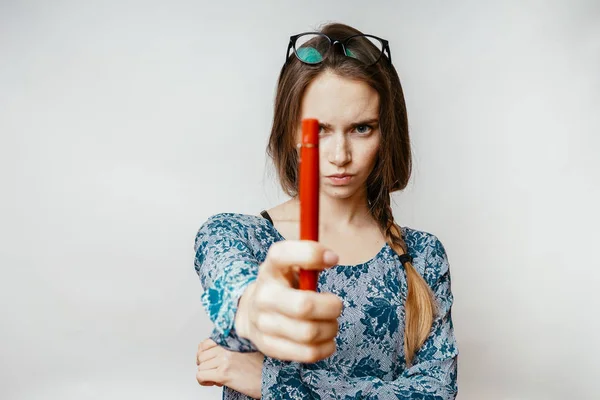 Una joven con gafas muestra un bolígrafo rojo y se ve enojada — Foto de Stock