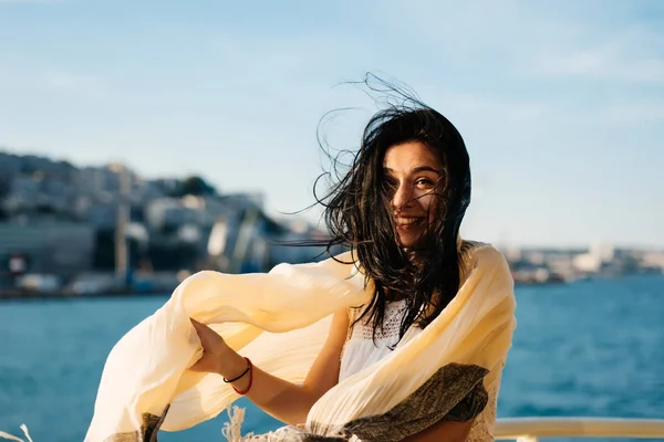 Ragazza divertente in una sciarpa nuota su una barca sullo sfondo della città di Istanbul — Foto Stock