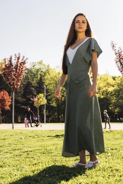 Jeune fille élégante dans une longue robe de marche à travers l'herbe verte dans le parc — Photo