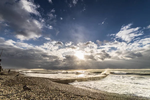 Contra el fondo del cielo con nubes blancas que arrasan el mar cerca de la playa rocosa —  Fotos de Stock