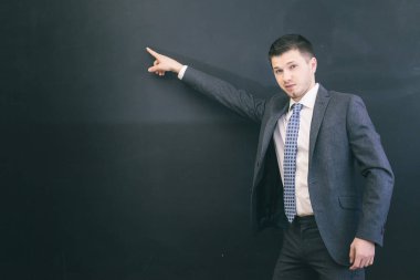 Takım elbiseli genç başarılı kendine güvenen adam onun parmağını Tebeşir tahtaya gösterir.