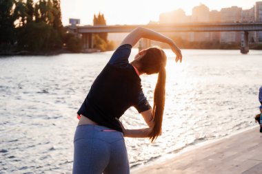 gün batımında nehrin yanında kaslar yoğurma sportif bir ince kız