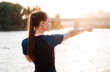 atletik kız güneş ışınlarının bir nehir tarafından kas kneads