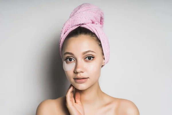 Aranyos szép lány, tiszta bőr, és egy rózsaszín törülközővel a fején néz a kamerába — Stock Fotó