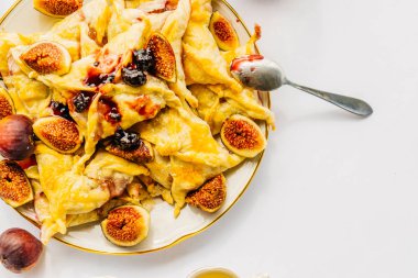 Beyaz bir masaya bir tabak sıcak börek ve incir ile var